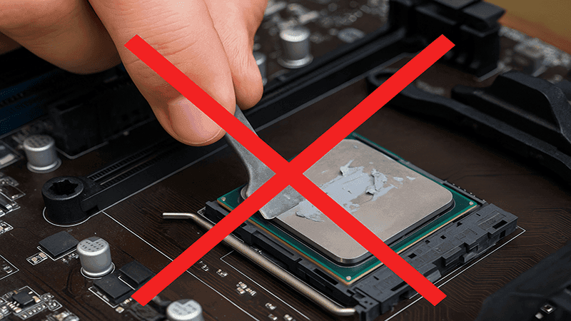 Person scraping thermal paste off a CPU incorrectly using a metal tool.